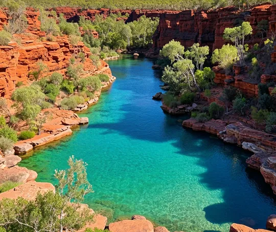 Clear turquoise river flowing between red rocky cliffs with green vegetation.
